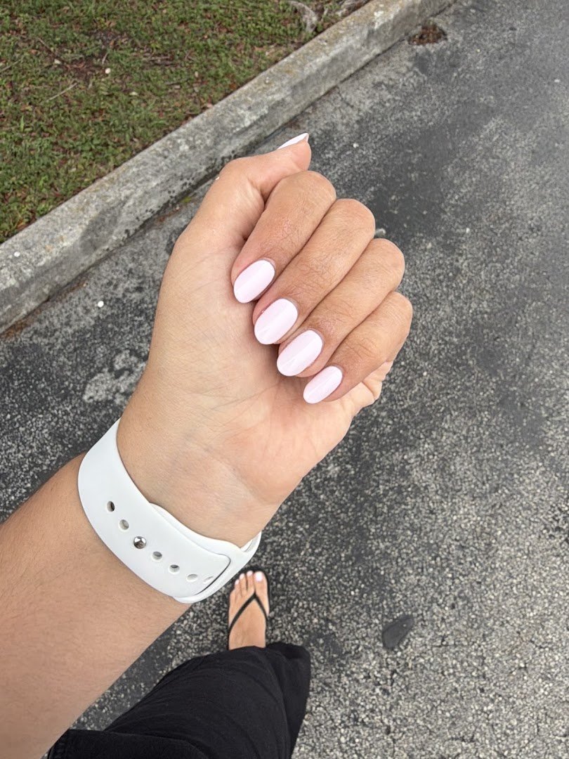 Nail technician shaping acrylic nails at a salon station.